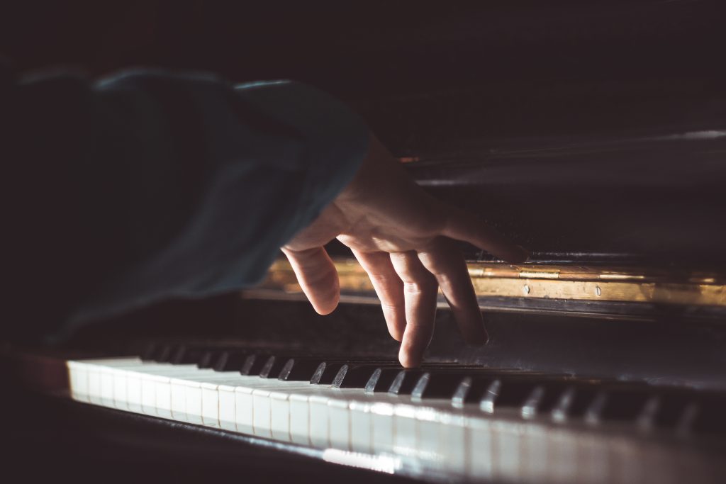 one male hand on the piano. The palm lies on the keys and plays the keyboard instrument in the music school. student learns to play. hands pianist. black dark background.
