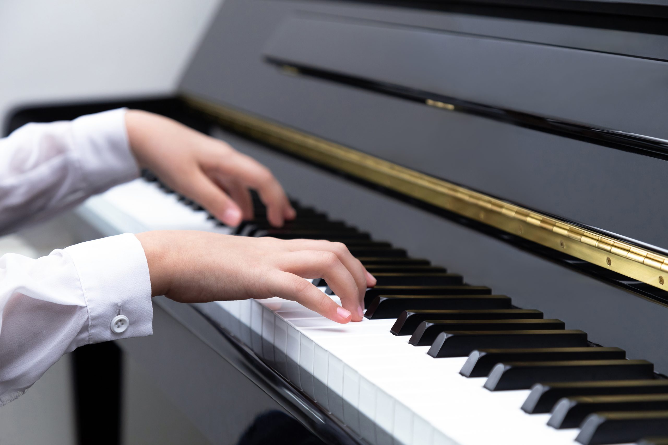Closeup of a young girl’s hands playing piano. Music education concept