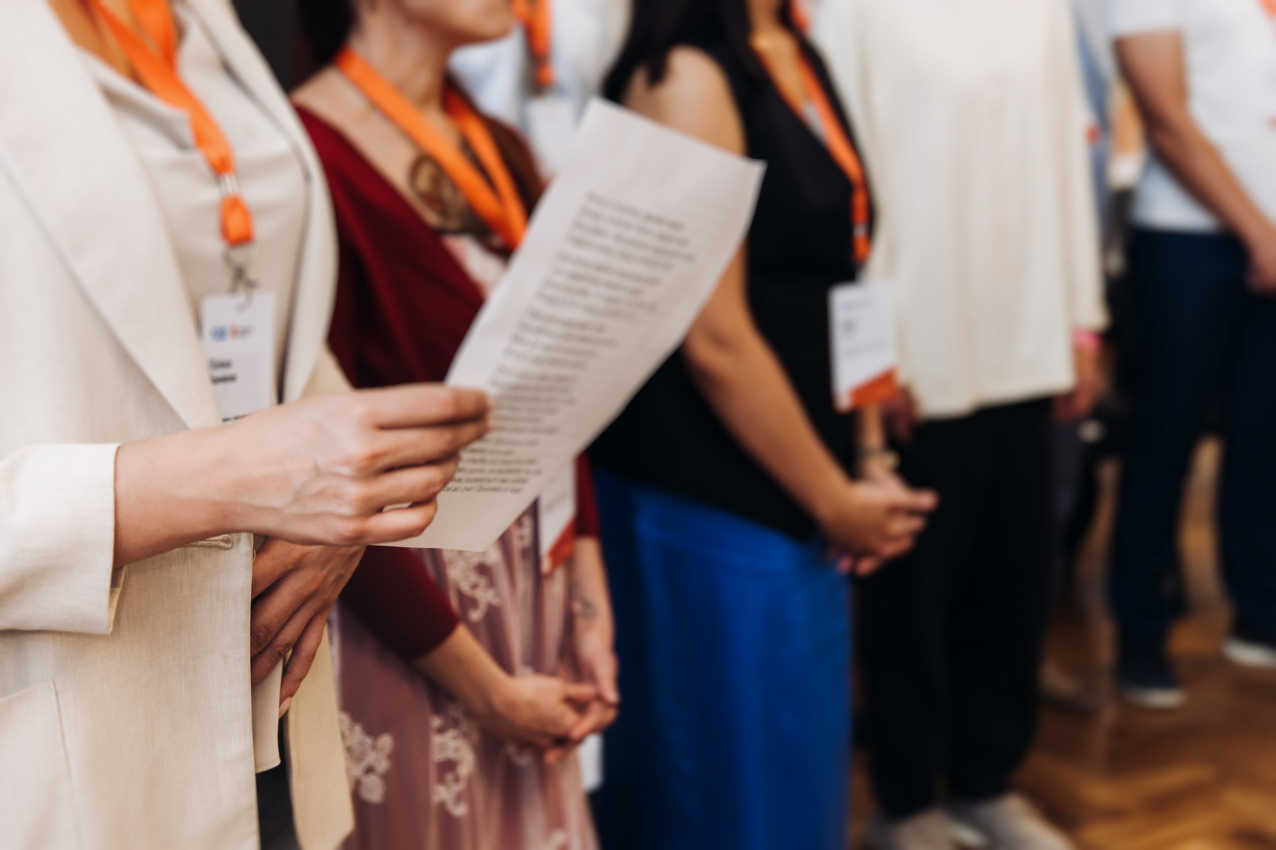 Choir rehearsal, vocal class singing in the auditorium hall, group of students on stage holding white sheets and singing, orchestra vocals class in music school with a teacher, adults sing in chorus